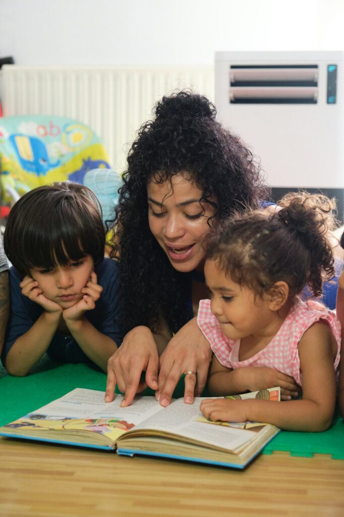 Teacher reading a story to her students lying on the floor